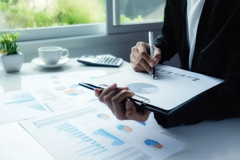 A person reviewing printed portfolio charts on a clipboard at a desk